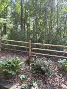 A rustic wood split-rail fence with wire mesh, perfect for gardens, installed by Cavitt Fencing in Concord, NC.