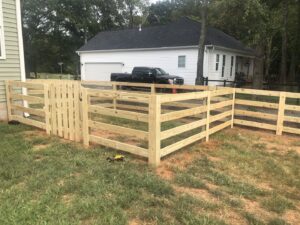 A new wood split-rail fence with wire mesh and a gate installed by Fenceitforu LLC in Matthews, NC.