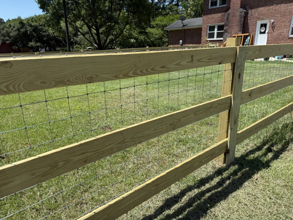 A newly installed wood split-rail fence with wire mesh by Fence & Custom Gatework LLC in Columbia, SC