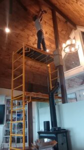 A worker on scaffolding installing or repairing a wood stove pipe for Western Expanse Chimney and Hearth in De Smet, ID.