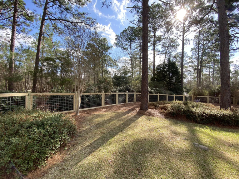 A newly installed wood and wire mesh fence in a residential backyard by Renegade Fencing, LLC in Jacksonville, NC.