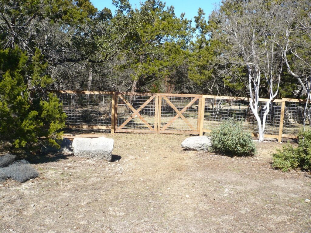 A custom wood and wire mesh double gate installed in a rustic setting by City Fence Co of San Antonio, TX