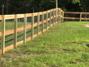 A rustic wood fence with wire mesh infill, suitable for farms or large properties, installed by Fencing & Railing 2 Corp in Orlando, FL.