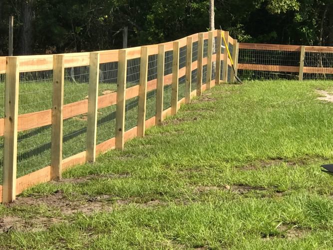 A rustic wood fence with wire mesh infill, suitable for farms or large properties, installed by Fencing & Railing 2 Corp in Orlando, FL.