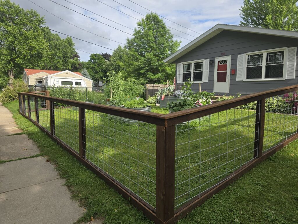 A stylish wood and wire mesh fence enclosing a garden area by Brothers Fence Co. in Madison, WI.