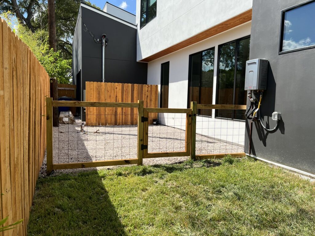 A newly installed wood and wire mesh fence with a gate by Good Neighbor Fencing and Construction in Austin, TX.