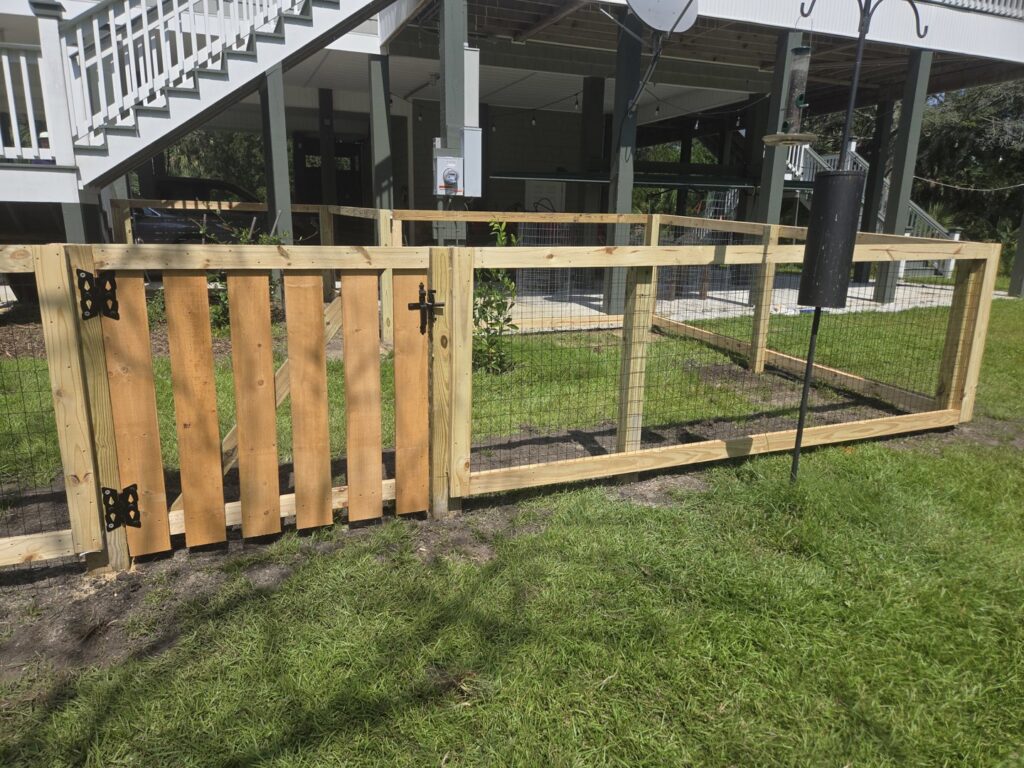 A wooden fence with wire mesh sections and a gate, installed by JB FENCE Brothers company llc in North Charleston, SC.