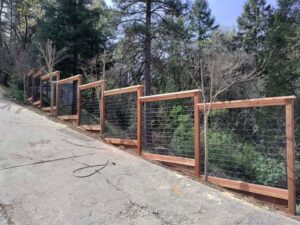 A wood and wire mesh fence installed on a sloped terrain by Sacramento Valley Fencing in Sacramento, CA.
