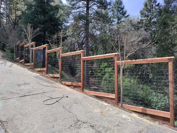 A wood and wire mesh fence installed on a sloped terrain by Sacramento Valley Fencing in Sacramento, CA.