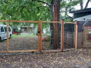 A rustic wood and wire mesh fence with a gate installed by Good Neighbor Fencing and Construction in Austin, TX.