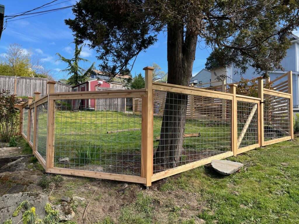 A wooden fence with wire mesh panels enclosing a garden area by Helmco Fences in Seattle, WA.