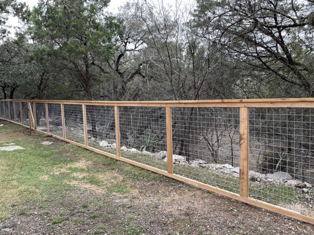 A long perimeter fence constructed with wood posts and wire mesh by City Fence Co of San Antonio, TX