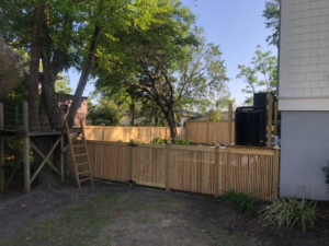 A wooden backyard fence with a gate, installed next to a house by Lowcountry Home Works843 LLC in Summerville, SC.
