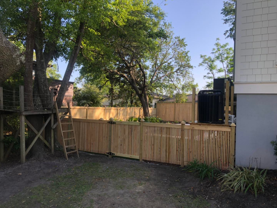 A wooden backyard fence with a gate, installed next to a house by Lowcountry Home Works843 LLC in Summerville, SC.