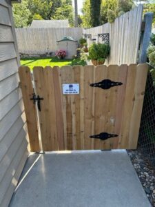 A custom wooden backyard gate with a Rio Fence Co. sign, installed in Lincoln, NE.