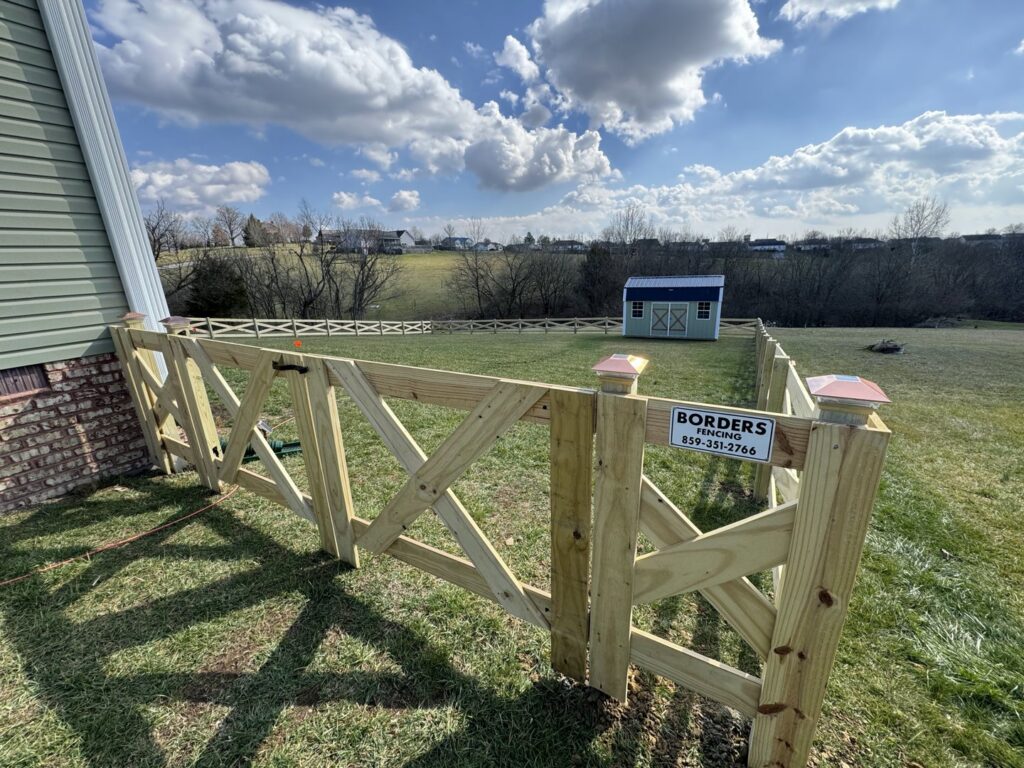 A newly installed wooden cross-buck style fence with a gate in a residential yard by Border Built Fencing in Florence, KY.