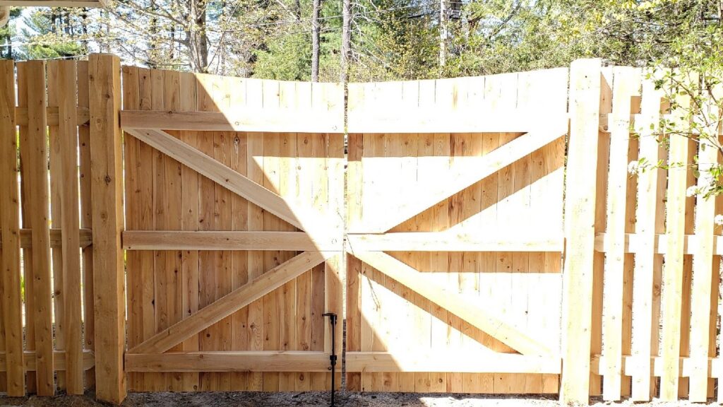 A sturdy wooden double gate with diagonal bracing, part of a new fence installation by Sullivan & Sons Fence LLC in Hudson, NH.