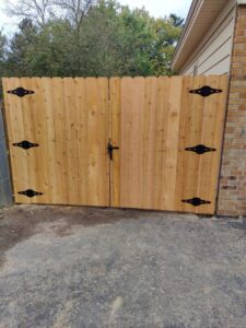 A custom wooden double gate with decorative black hinges, installed by Metrofence in Grand Rapids, MI.