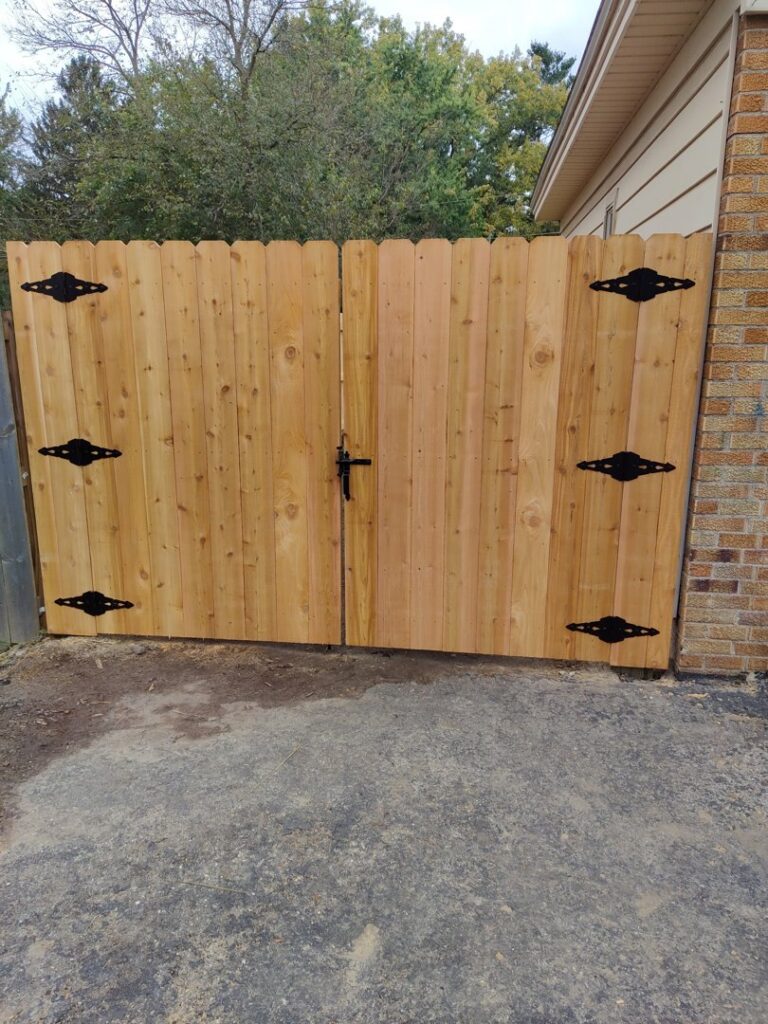 A custom wooden double gate with decorative black hinges, installed by Metrofence in Grand Rapids, MI.