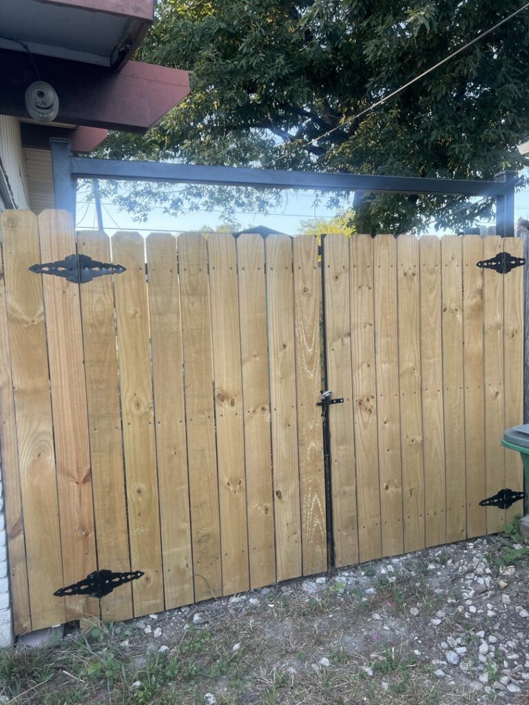 A custom wooden double gate with a sturdy metal frame installed by Serrato's Fence & Welding in San Antonio, TX.