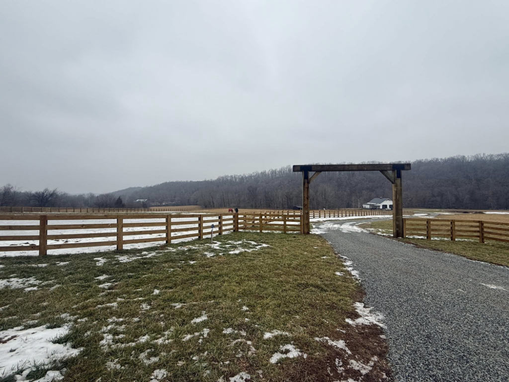 A newly installed wooden farm fence with a grand archway entrance by Richards Fencing in Lynnville, TN
