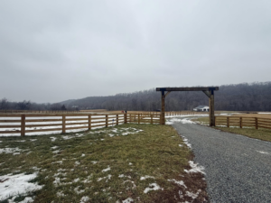 A newly installed wooden farm fence with a grand archway entrance by Richards Fencing in Lynnville, TN