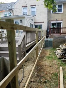 A wooden fence under construction next to a residential deck and house by Concord Fence Llc in Wilmington, DE