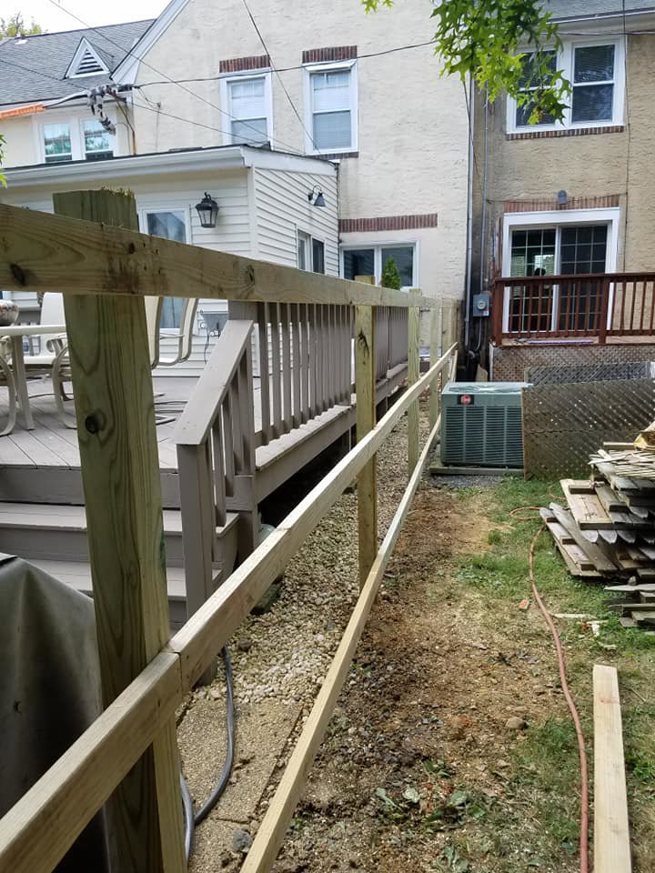 A wooden fence under construction next to a residential deck and house by Concord Fence Llc in Wilmington, DE