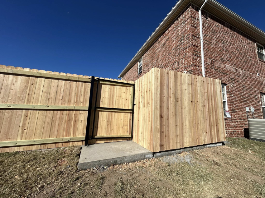A wooden privacy fence with a matching gate and small enclosure installed by Timber Wolf Fence Co. in Rogers, AR.