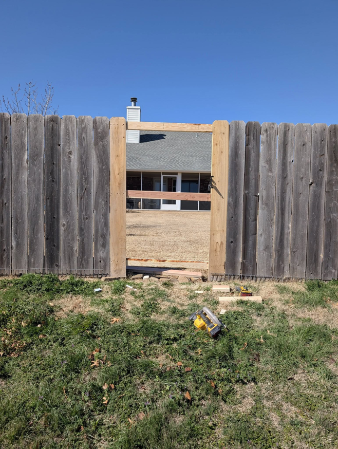 An opening in a wooden fence prepared for gate installation by Black and Sons fencing in Indiahoma, OK.