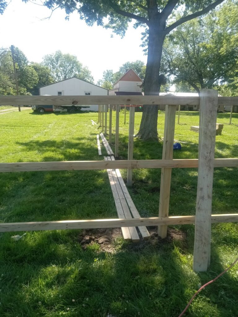 Wooden fence posts and planks laid out, showing a fence installation in progress by NBBJ Fence LLC in Bluffton, IN.