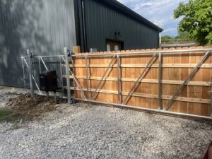 A wooden fence with a metal frame sliding gate installed by Brothers Gate Operators and Services LLC in Olathe, KS.