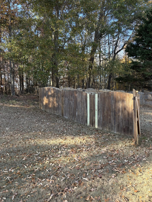 A wooden fence showing new panel replacements and a detached section, indicating repair work by Myers & Dunlap Fence Repair in Greenville, SC.