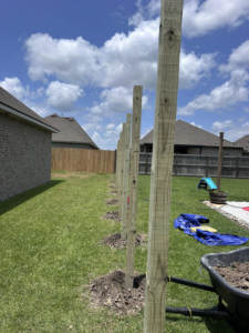Wooden fence posts being installed in a backyard by Gator Fence Co. in Miami, FL