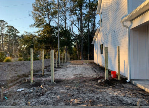 Wooden fence posts installed in the ground, showing a fence installation in progress by Heavenly Gates Construction LLC in Miami, FL