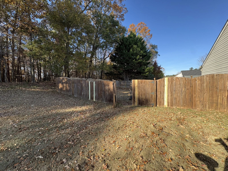 A wooden fence in a backyard showing sections of new repair work by Myers & Dunlap Fence Repair in Greenville, SC.