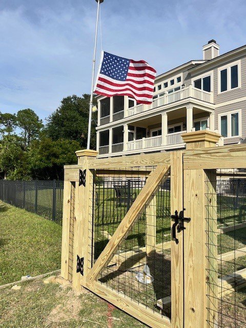 A wooden fence with wire mesh and a gate, showcasing work by Crompton Fence Company in Charleston, SC.