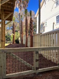 A wooden fence with a wire mesh gate providing access to a residential property by Stono Fencing & Exteriors in Johns Island, SC
