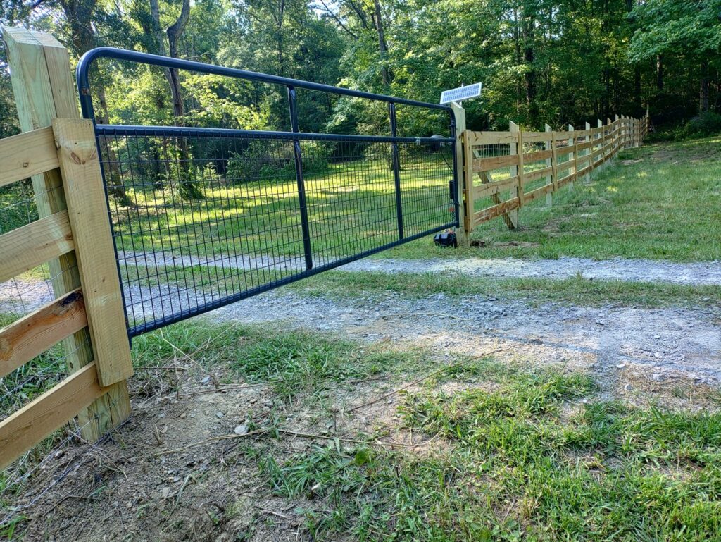 A wooden fence with a black metal automatic gate, possibly solar-powered, installed by Kelley Fence and Gate in Eva, AL.