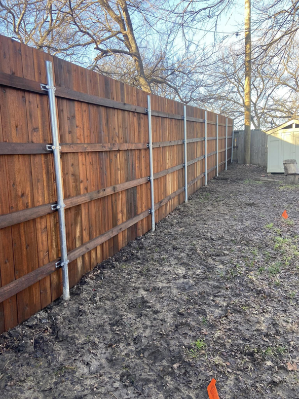 A wooden fence reinforced with metal posts during installation by Stevenson Brothers Fencing in Fort Worth, TX