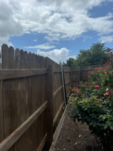 A sturdy wooden fence featuring a new metal support post installed by T&G Outdoor Services in Austin, TX.