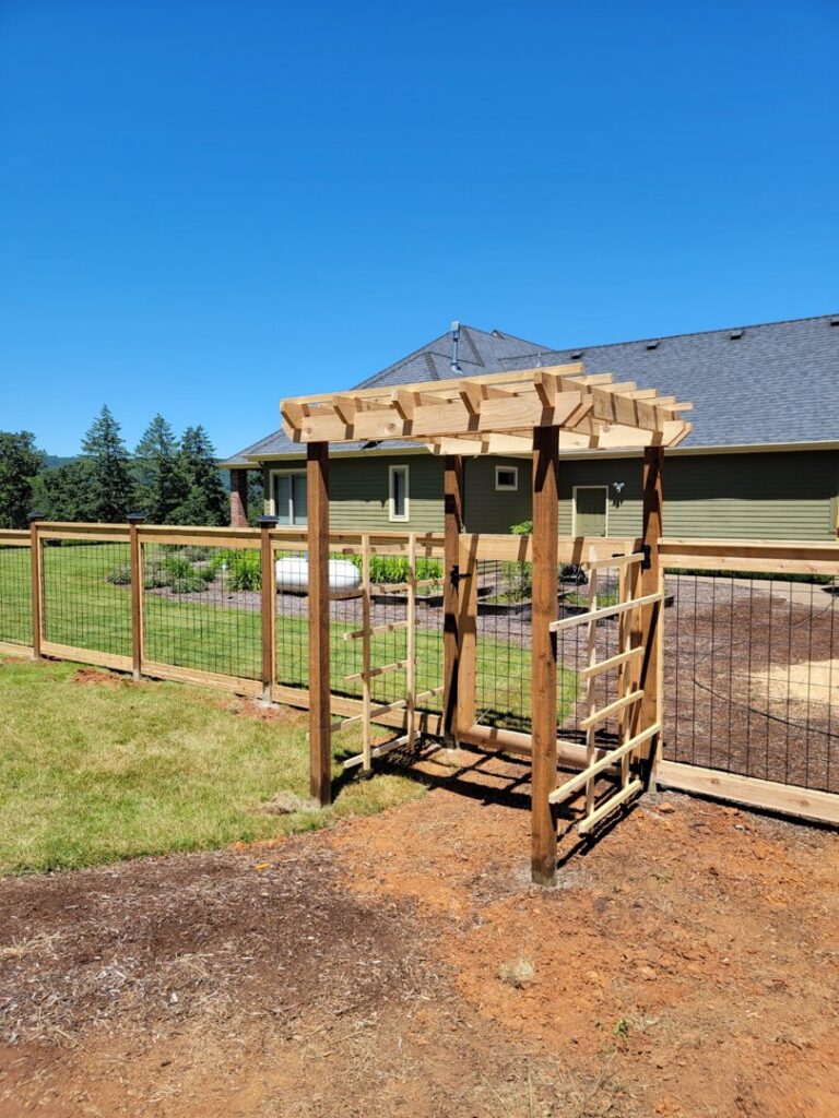 A custom wooden fence with wire mesh and a matching arbor gate installed by Faxon Fencing in Corvallis, OR.