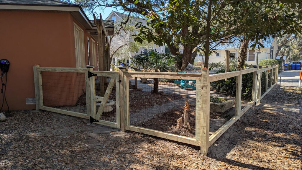 A wooden fence with wire mesh and a matching gate installed by Gifford Contracting & Repair - Custom Privacy Fencing in Goose Creek, SC.
