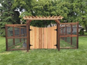 A custom wooden garden gate with a pergola top and wire mesh fencing installed by MN Mike's Fence and Repair in Lakeville, MN.