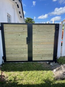 A wooden gate with a black metal frame and horizontal slats installed by Miami Fence Installation Contractors in Miami, FL.