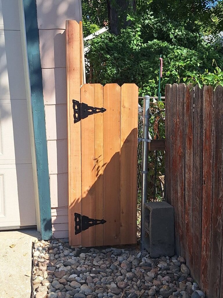 A custom wooden gate installed next to an existing chain-link fence by Pride Fence in Peabody, MA.