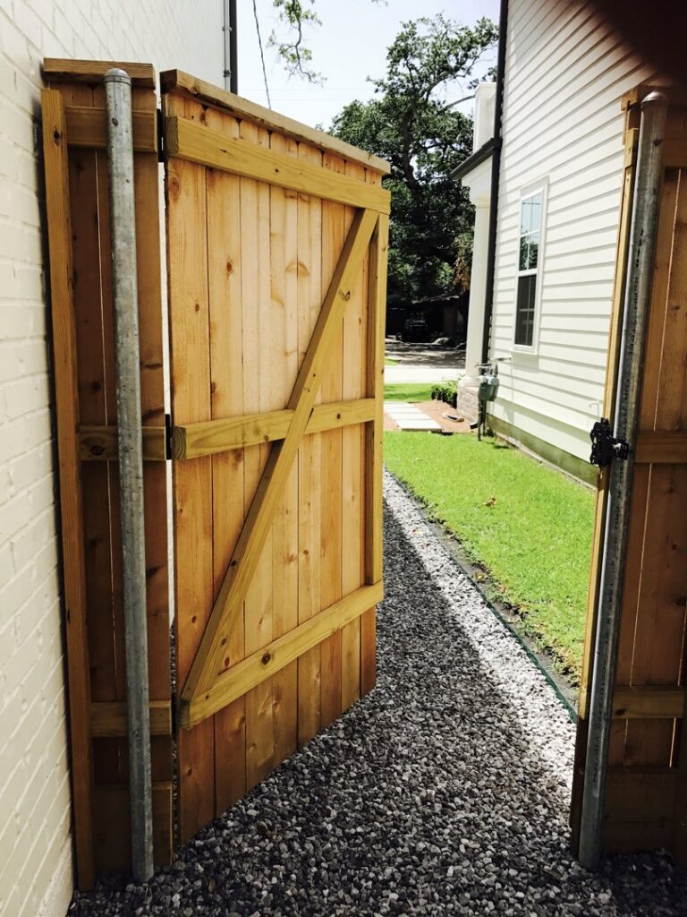 A newly installed wooden gate with a gravel path by Amko Fence Co. in Kenner, LA.