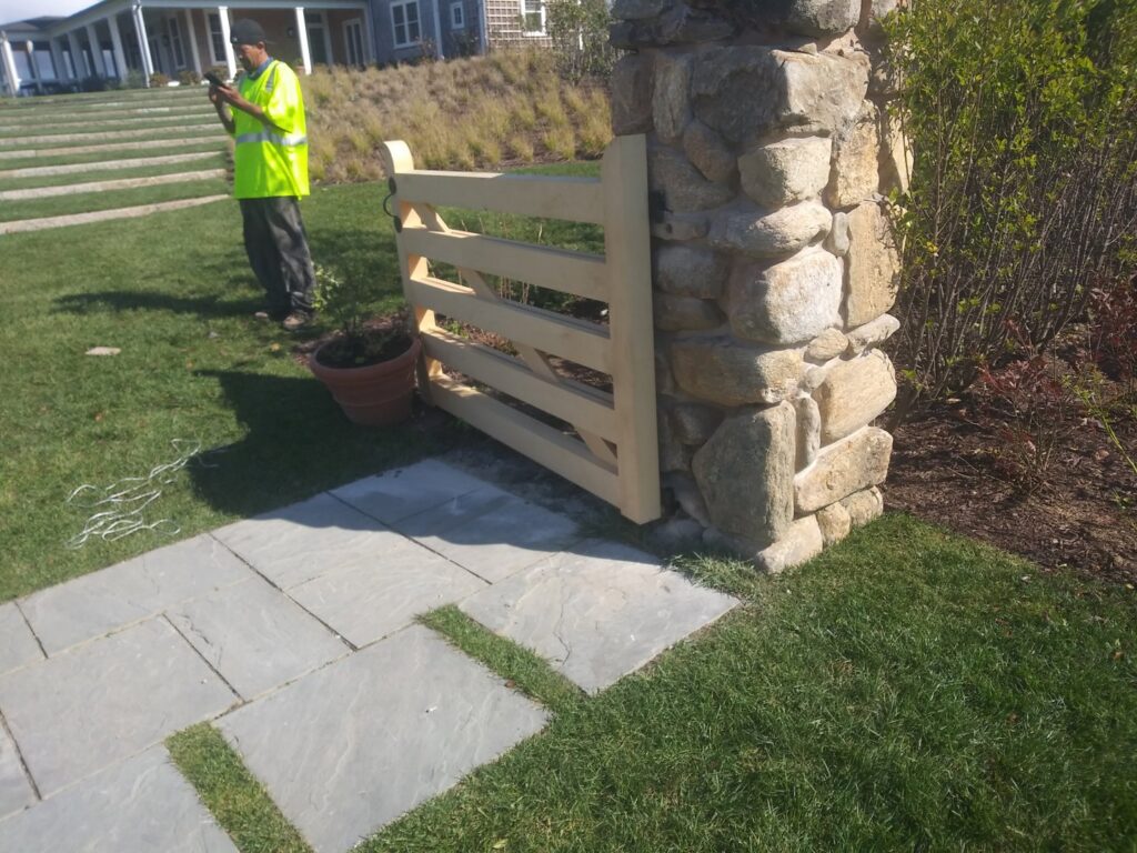 A custom wooden gate integrated into a stone pillar, installed by Reilly Fence Inc in Cranston, RI.