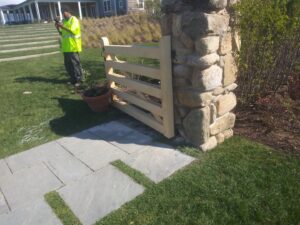 A custom wooden gate integrated into a stone pillar, installed by Reilly Fence Inc in Cranston, RI.