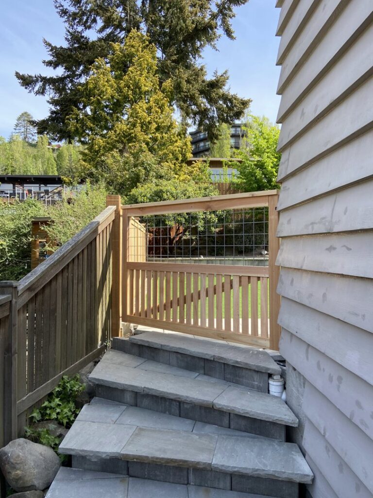 A wooden gate with a wire mesh top section at the top of stone steps by Helmco Fences in Seattle, WA.
